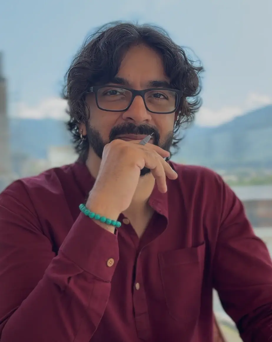 Portrait of Deepak Atri in a maroon kurta, resting his chin on his hand
